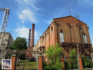 Foto eines Kraftwerks auf der Halbinsel Andrejsala in Riga, Lettland, historische Backstein-Bausubstanz, Außenansicht Fabrikshalle mit zwei Schloten